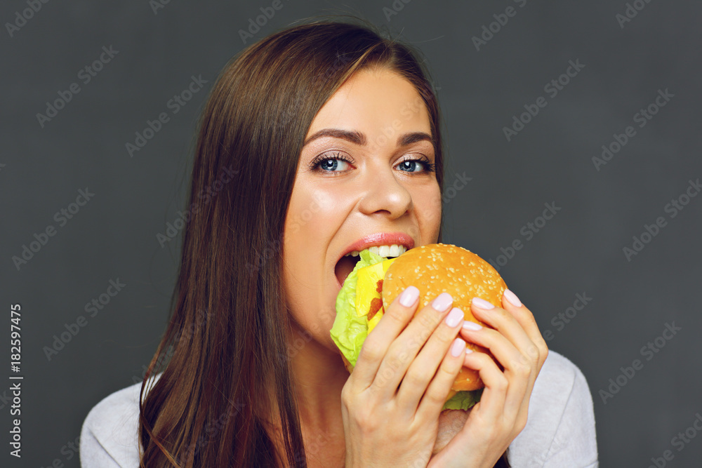 Young woman biting big burger isolated portrai Young woman biting big burger isolated portrai