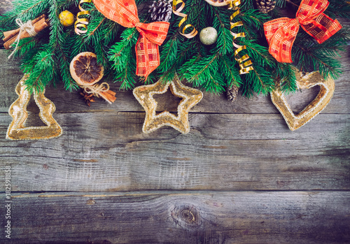 Vintage Christmas background with fir branches, new year decor, toys, candied fruits and spices on the old rustic wooden backdrop. Top view with copy space. Selective focus,