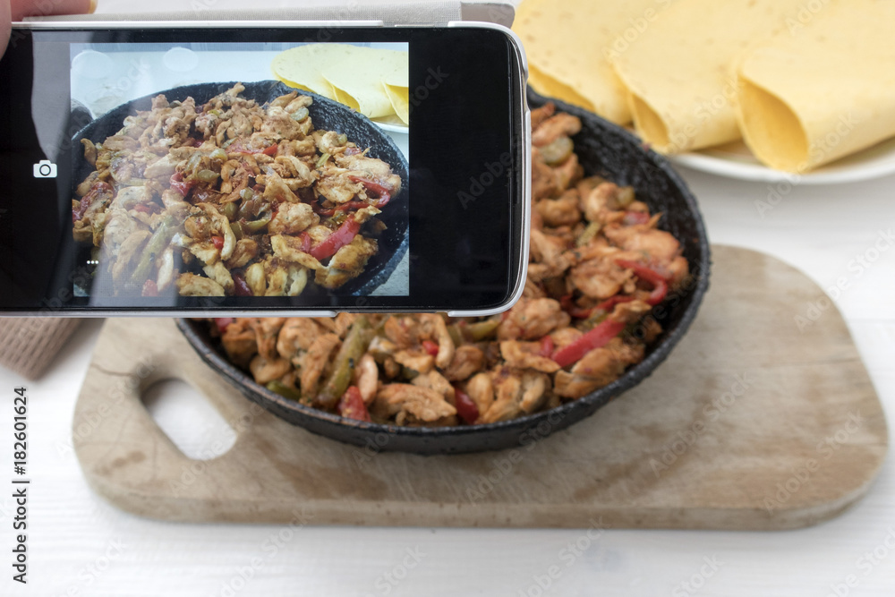 Photographing on the phone chicken stew with red and green pepper, with red onion, pickled cucumber and spices in a frying pan. Photographing on the phone chicken stew with red and green pepper, with red onion, pickled cucumber and spices in a frying pan.