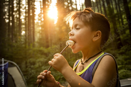 Kid eating a marshmallow while camping