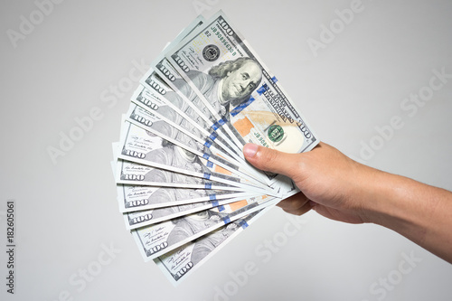 US dollar bills money in hand on white background. Close up businessman hand holding or giving many one hundred dollar banknotes