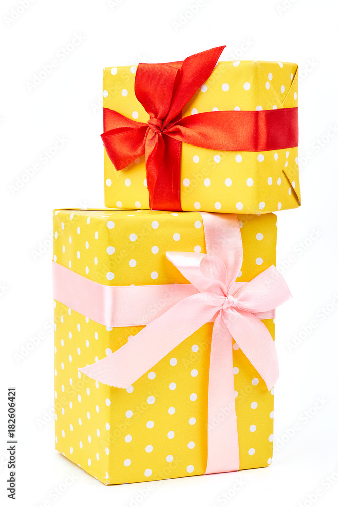 Two yellow dotted gift boxes. Presents are packed in colored paper. Polka-dot pattern tied with a beautiful pink and red ribbons over white background. Two yellow dotted gift boxes. Presents are packed in colored paper. Polka-dot pattern tied with a beautiful pink and red ribbons over white background.
