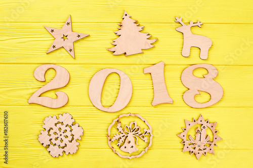 Number 2018 and wooden New Year figures. Christmas background with decorations. Wooden handmade carved figures of star, deer, spruce, candles on colored background.