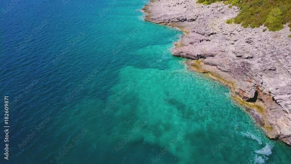 Aerial of rocky coastline and turquoise sea. Sea bottom is visible through transparent water Aerial of rocky coastline and turquoise sea. Sea bottom is visible through transparent water