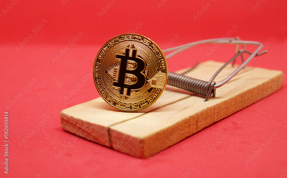 Mousetrap with gold bitcoin on red background.