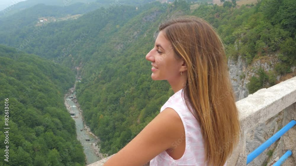 Young Woman Looking At The Mountains Standing On A Bridge Over A Deep Canyon Young Woman Looking At The Mountains Standing On A Bridge Over A Deep Canyon