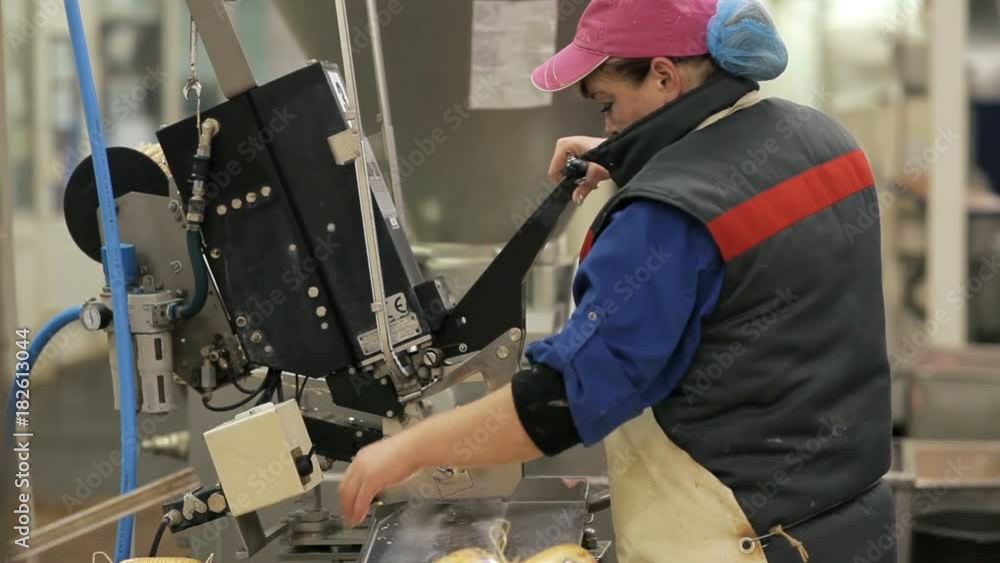 Worker produces sausage on a automated food production equipment Worker produces sausage on a automated food production equipment