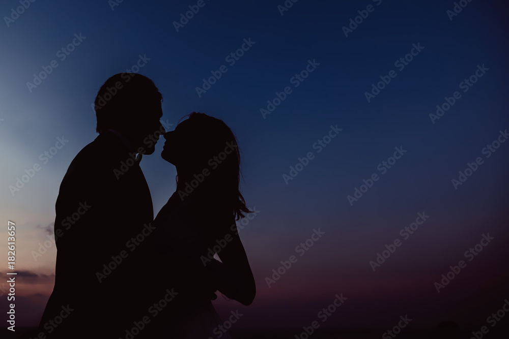 silhouettes of woman and man and evening sky after sunset