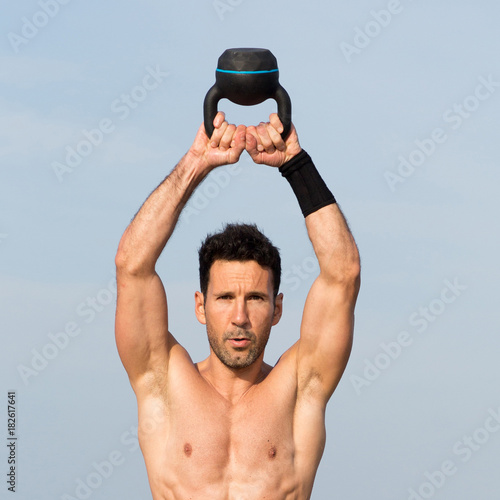 man making kettlebell exercise on the beach photo