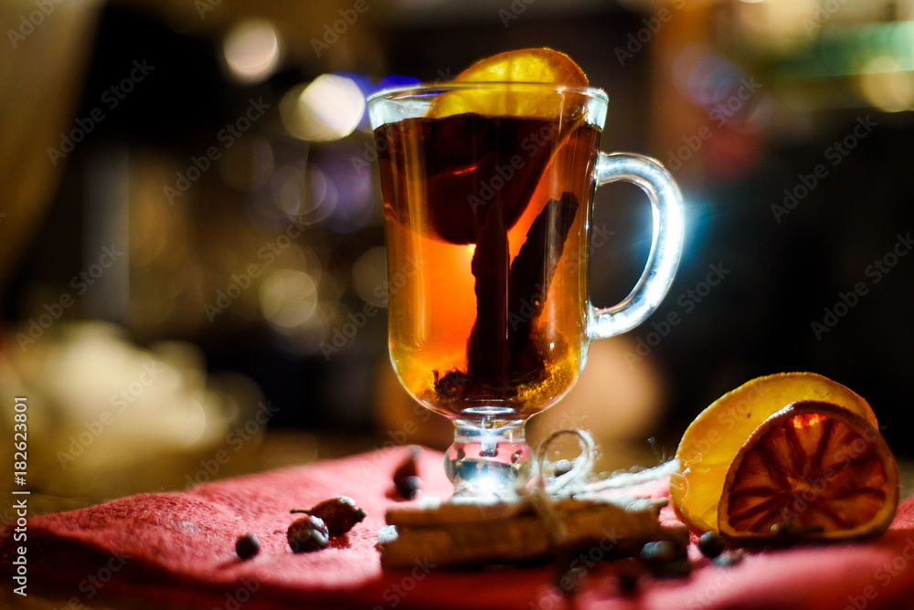 A glass of mulled wine on a bar counter with lemon and a cinnamon stick A glass of mulled wine on a bar counter with lemon and a cinnamon stick