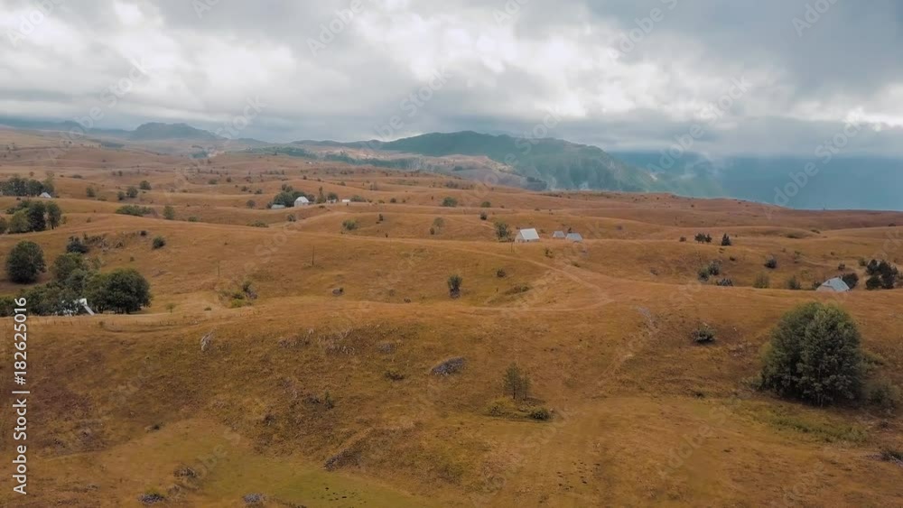 Aerial of hilly plateau in upland covered with dry grass. Clouds cover mountains' tops Aerial of hilly plateau in upland covered with dry grass. Clouds cover mountains' tops