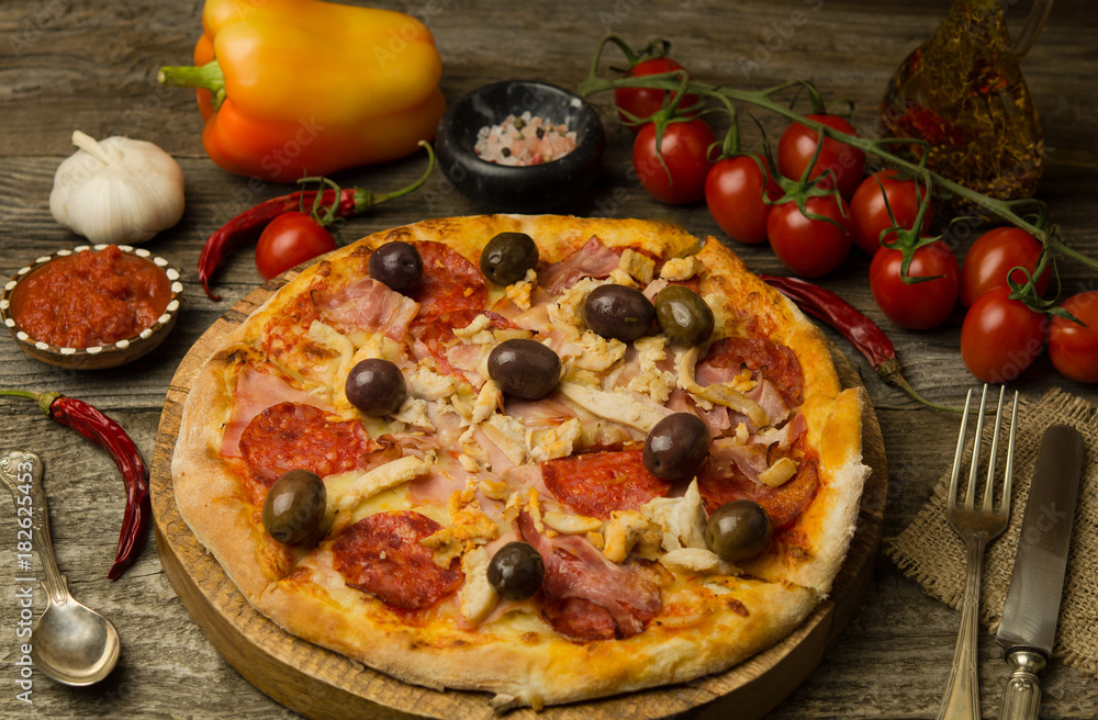 Pizza with pepperoni, bacon, chicken on dark wood background. Hot homemade delicious pizza 