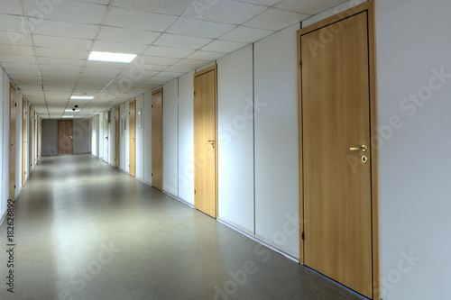 Tableau sur toile Long office hallway with a lot of yellow wooden doors.