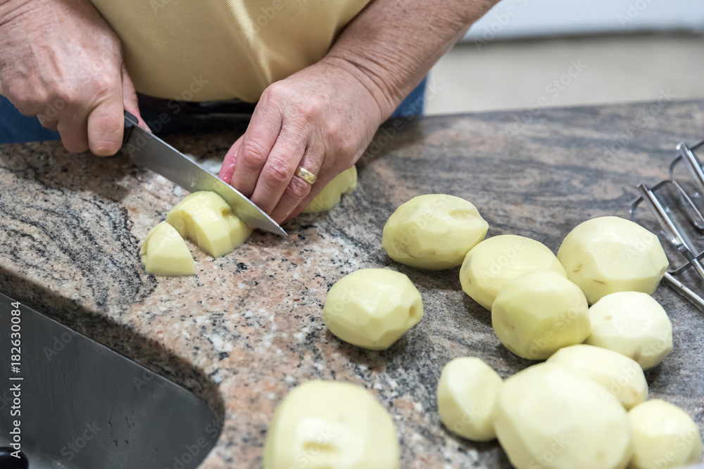 A man cutting potatoes on a kitchen counter