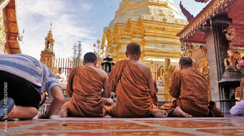 Canvas Print Monks sitting and praying in front of temple in Thailand