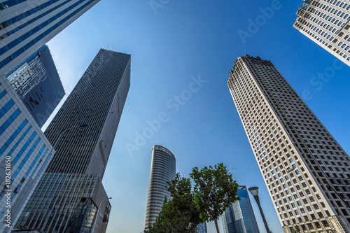 Bottom view of modern skyscrapers in business district against blue sky. © hallojulie