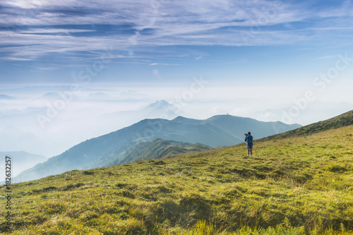 A hiker admiring and watching a foggy mountain view, Brescia province, Lombardy district, Italy