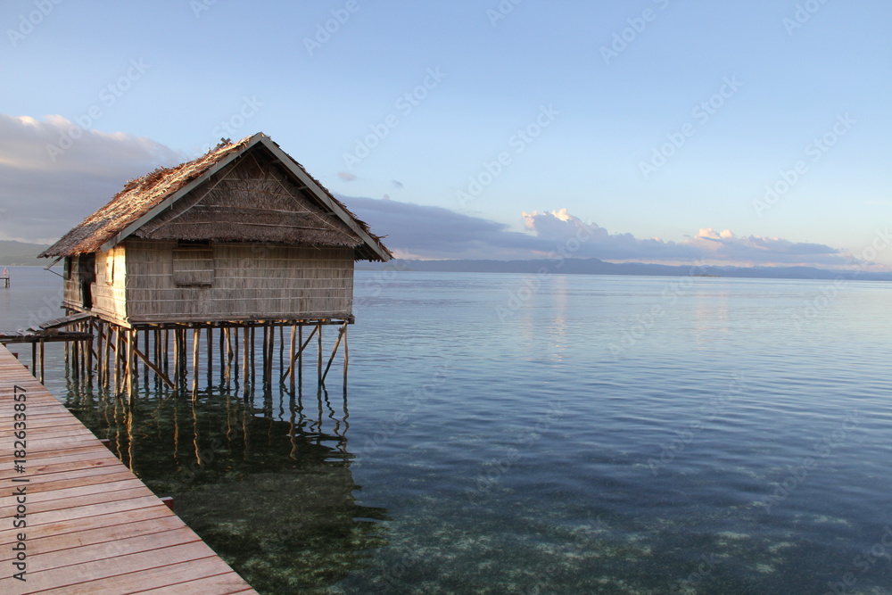 Beautiful Sunset with Ocean Over-Water Bungalows and Trees in Raja Ampat Indonesia
