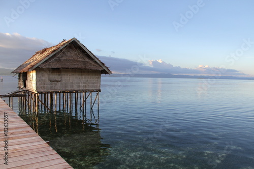 Beautiful Sunset with Ocean Over-Water Bungalows and Trees in Raja Ampat Indonesia