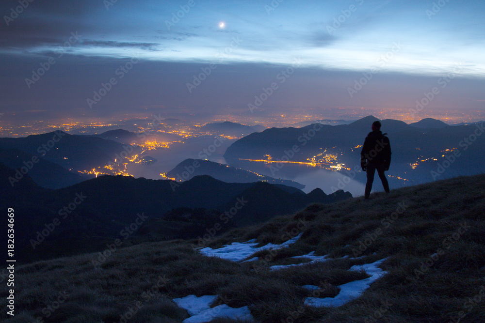 A hiker admiring and watching lake Iseo with Montisola at dusk, Brescia province, Lombardy district, Italy