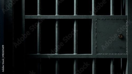 A static camera closeup of a heavy welded iron jail cell door slamming shut on a dark moody background photo