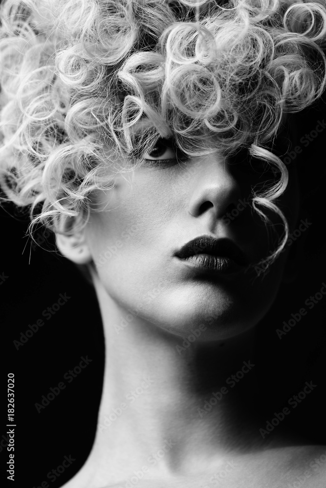 Barber. Black and white portrait of a young girl with stylish curly hairstyle on black background