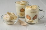 Freshly made banana pudding in the circles and the slices of banana on a white table.