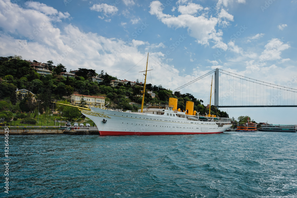 Antique boat anchored to a city's coastline with a bridge in the