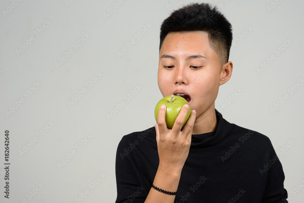 Portrait of Asian young tomboy holding healthy green apple fruit Portrait of Asian young tomboy holding healthy green apple fruit