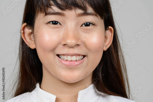 Portrait of beautiful young Asian woman against white background