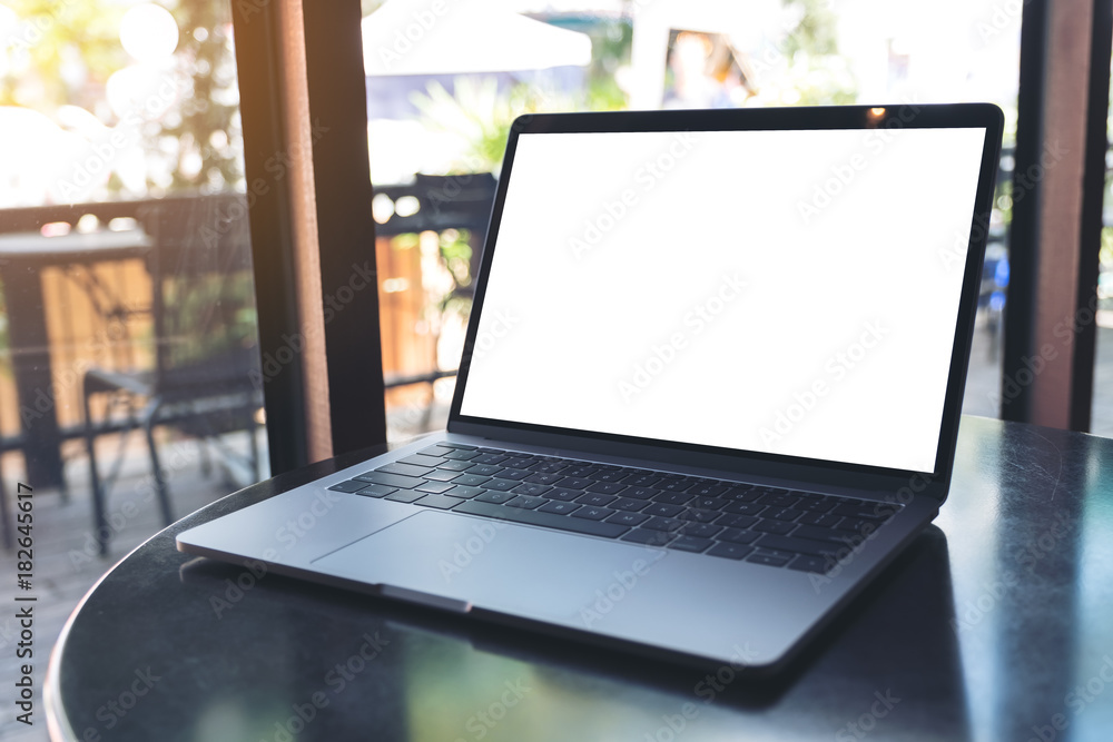 Mockup image of laptop with blank white screen on wooden table near by window in modern cafe Mockup image of laptop with blank white screen on wooden table near by window in modern cafe