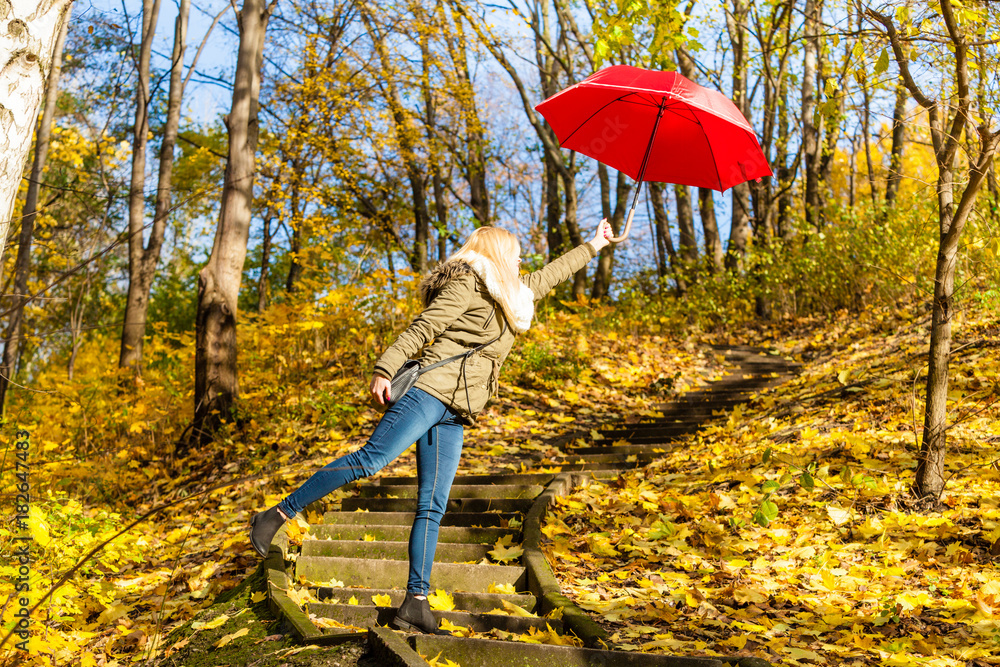 Woman walking in park with umbrella, strong wind Woman walking in park with umbrella, strong wind