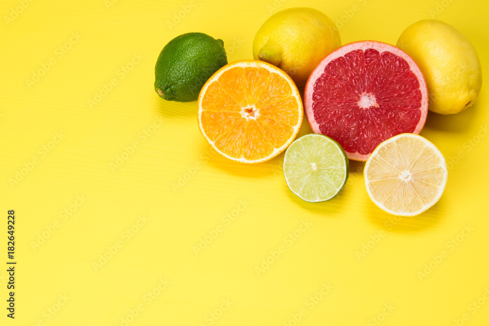red grapefruit, orange orange and yellow and green slices of lime, on a yellow background red grapefruit, orange orange and yellow and green slices of lime, on a yellow background