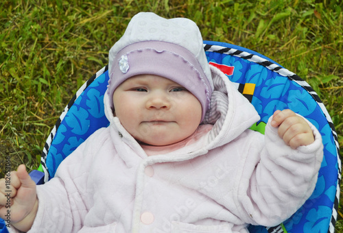 Little child in a hat on a background of green grass.