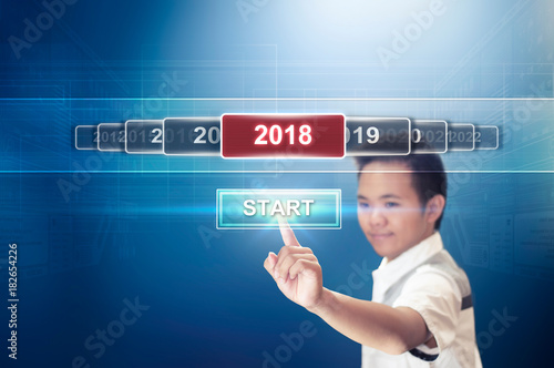 Start the New Year 2018. New Year Concept of A Boy Pressing or Touching the Start Button Hologram to Start the New Year 2018