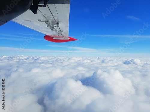 wing of a plane against a blue sky and clouds