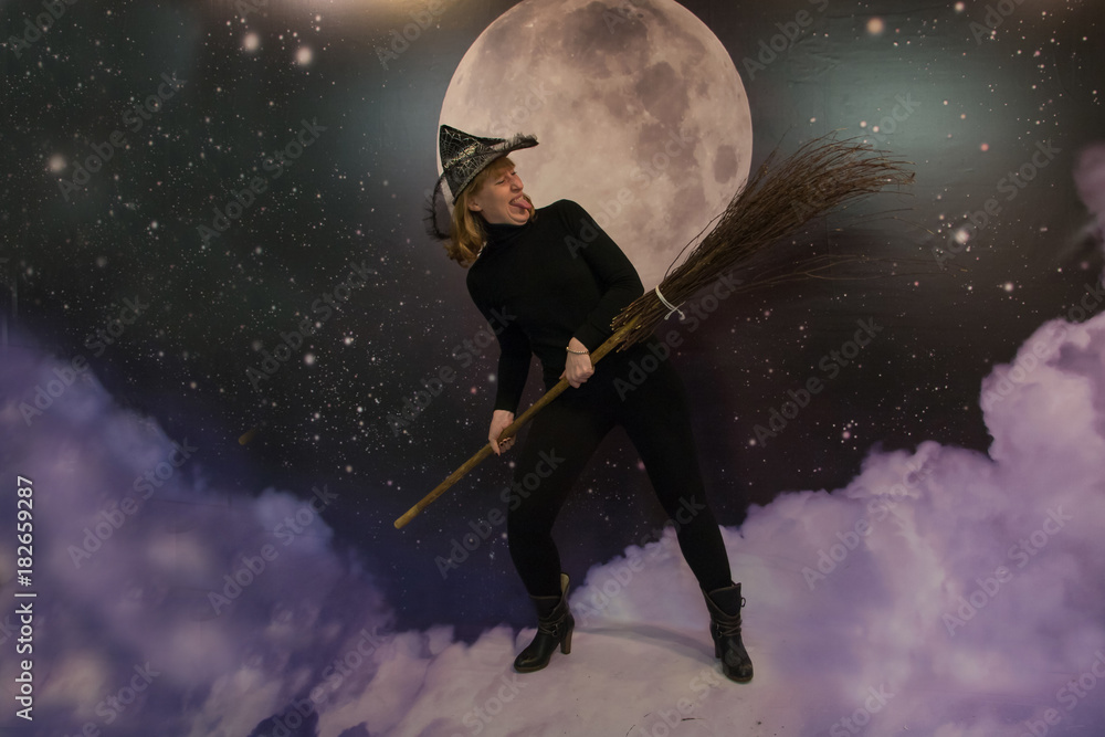 Girl in black clothes and hat depicts a witch Girl in black clothes and hat depicts a witch