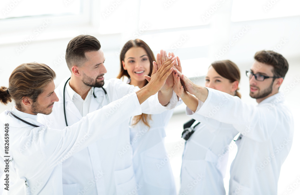 group of doctors giving each other a high five. group of doctors giving each other a high five.
