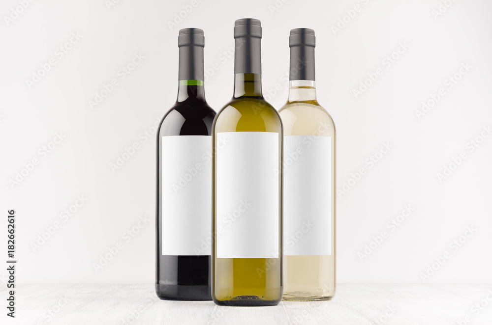 Set wine bottles - transparent, green, black- with blank white labels on white wooden board, mock up. Template for advertising, design, branding identity.