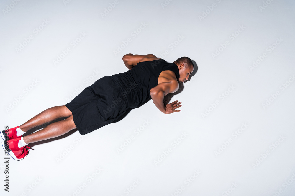 high angle view of young african american sportsman doing push ups isolated on grey high angle view of young african american sportsman doing push ups isolated on grey