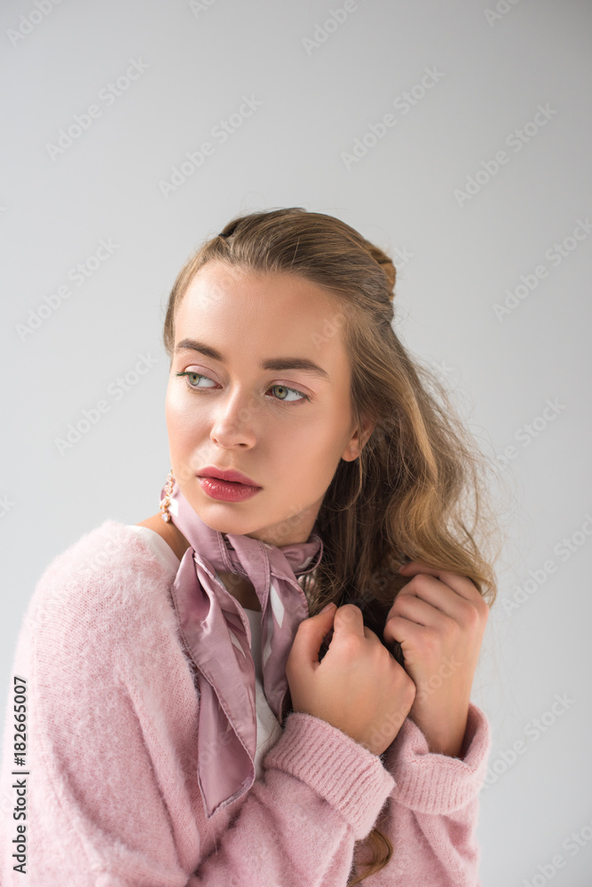 attractive woman in pink shirt and scarf looking away isolated on gray