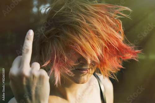 Red-haired girl showing middle finger gesture. Redhead Woman showing a fuck you off sign. Close up