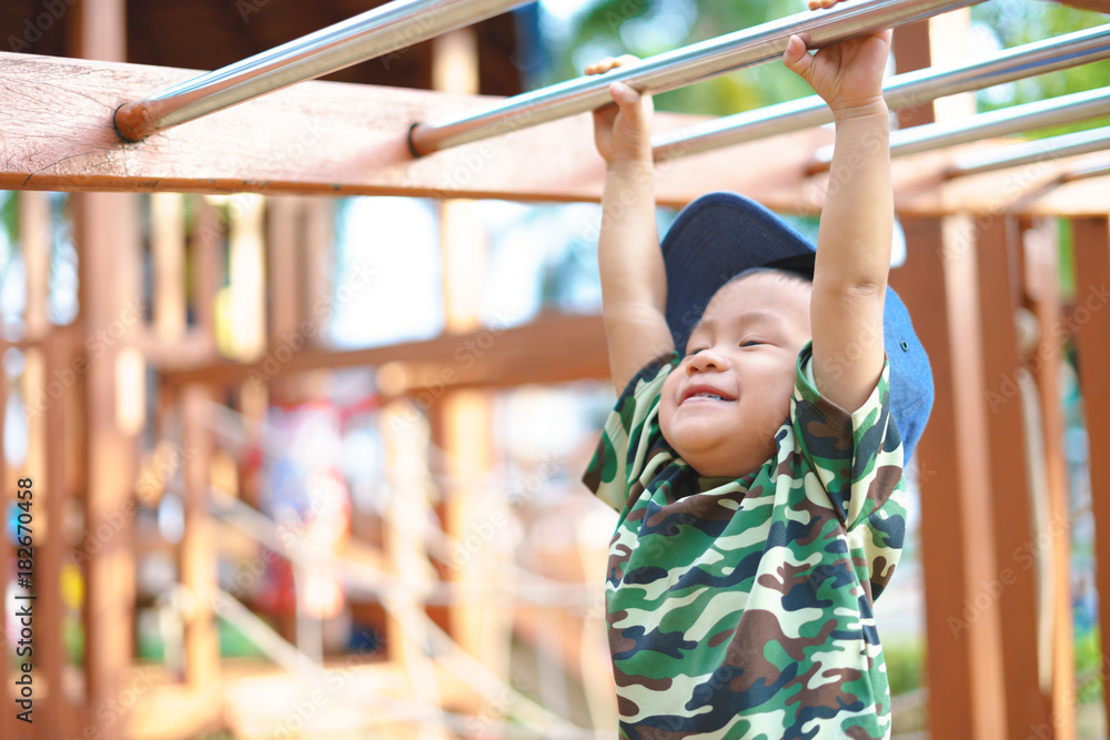 Fototapeta premium Asian boy about 1 year and 9 months in military suit playing at kid training playground