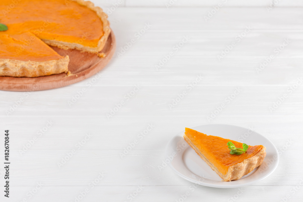 Pumpkin pie Homemade dessert Autumn delicious. Piece of traditional cake with cut pumpkin on white wooden background. Vegetarian food. Horizontal banner for thanksgiving, fall congratulation card Pumpkin pie Homemade dessert Autumn delicious. Piece of traditional cake with cut pumpkin on white wooden background. Vegetarian food. Horizontal banner for thanksgiving, fall congratulation card