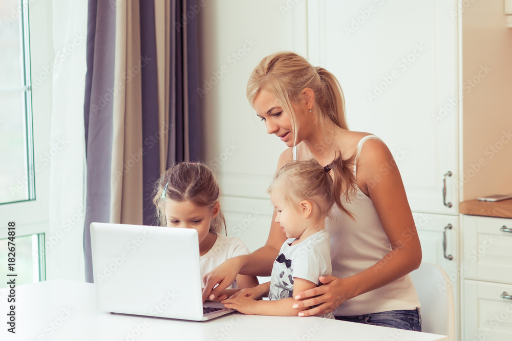 Young happy family using laptop while sitting at kitchen at home. Little children girl watching cartoons with parents Young happy family using laptop while sitting at kitchen at home. Little children girl watching cartoons with parents