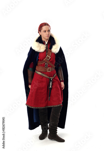 portrait of a red haired girl wearing medieval warrior outfit, studio background.