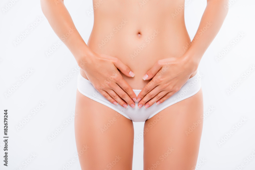 Concept of bodycare gynecology and woman's health. Cropped close up photo of woman's hand touching lower part of her abdomen, isolated on white background