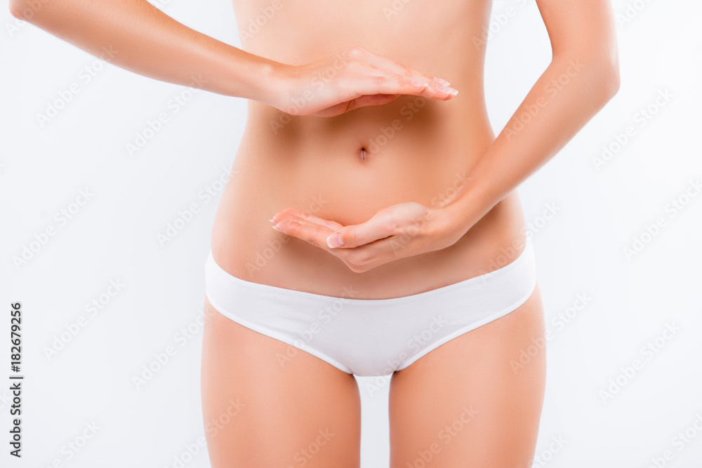 Concept of healthy eating. Close up cropped photo of beautiful woman's slim stomack, using hands she is showing a balance in her microflora and bowel, isolated on white background
