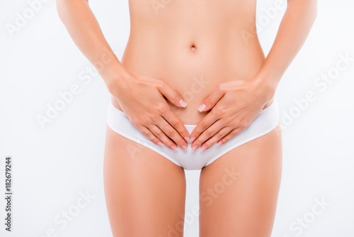 Concept of bodycare gynecology and woman's health. Cropped close up photo of woman's hand touching lower part of her abdomen, isolated on white background © deagreez