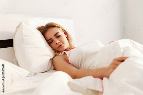 Pretty blonde sleeps lying in the white bed